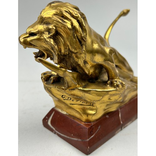 181 - A SCULPTURAL GILT BRONZE OF A LION, mounted on a red marble base and signed indistinctly.

16cm in l... 