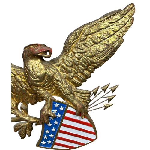 213 - A GILT PAINTED AMERICAN EAGLE WALL HANGING, above a United States Stars and Stripes with five arrows... 