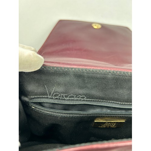 28 - A VINTAGE VERSACE BURGUNDY LEATHER FLAP BAG, with central Medusa head emblem and leather strap.

26c... 