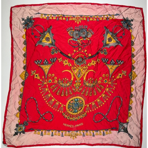 132 - A LARGE VINTAGE HERMES SILK SCARF, red, gold and pink depicting various articles of archaic jeweller... 