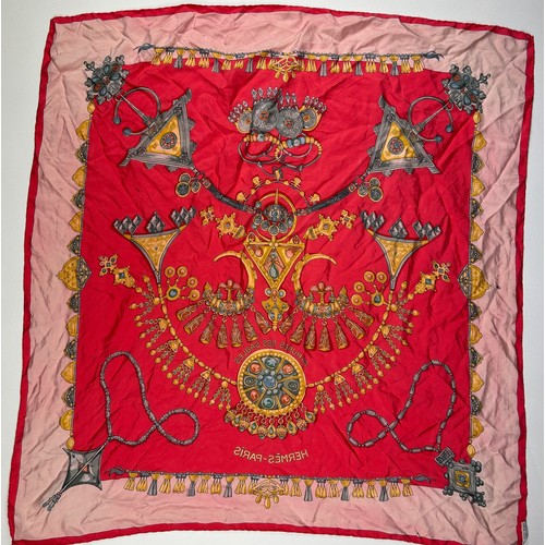 132 - A LARGE VINTAGE HERMES SILK SCARF, red, gold and pink depicting various articles of archaic jeweller... 