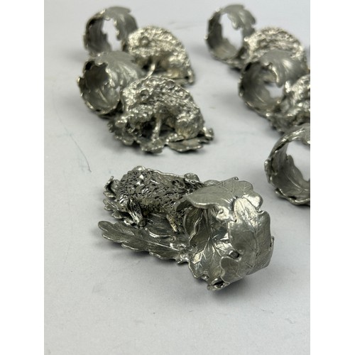 123 - A SET OF NINE SILVER PLATED NAPKIN RINGS REALISTICALLY FIGURED IN THE FORM OF HOGS ON LEAVES, in the... 