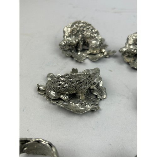 124 - A SET OF FIVE SILVER PLATED NAPKIN RINGS REALISTICALLY FIGURED IN THE FORM OF HOGS ON LEAVES, in the... 