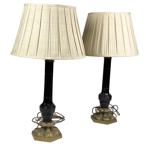 155 - A PAIR OF EMPIRE DESIGN RED GLASS TABLE LAMPS, mounted on heavy brass bases with shades