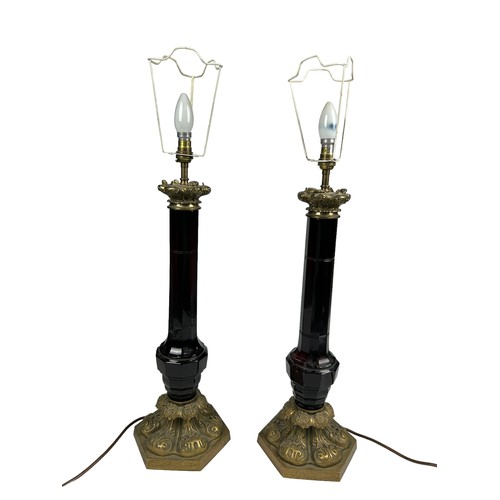 155 - A PAIR OF EMPIRE DESIGN RED GLASS TABLE LAMPS, mounted on heavy brass bases with shades