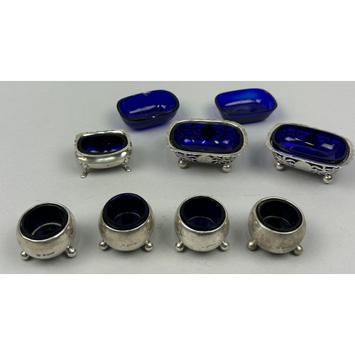 65 - A COLLECTION OF SILVER SALT CELLARS AND MUSTARD POTS, each with blue glass inserts (7) 

The salt ce... 