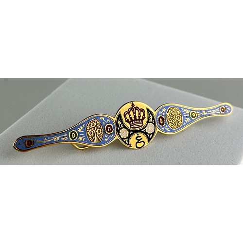 41 - A PERSIAN YELLOW METAL AND ENAMELLED BROOCH, 

Decorated with a crown and flowers, housed inside a b... 