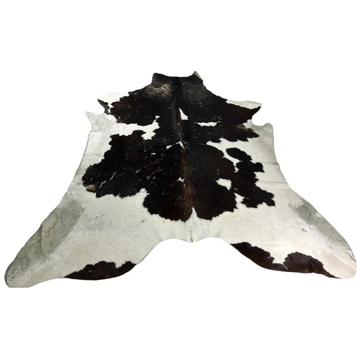 555 - A COWHIDE RUG ALONG WITH A SMALL COWHIDE UPHOLSTERED FOOTSTOOL (2)

Some damage to rug. 225cm x 190c... 