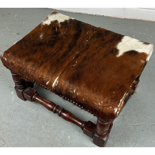 555 - A COWHIDE RUG ALONG WITH A SMALL COWHIDE UPHOLSTERED FOOTSTOOL (2)

Some damage to rug. 225cm x 190c... 