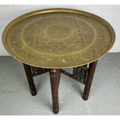 478 - A 19TH CENTURY MOROCCAN FOLDING TABLE, with a brass tray top, 64cm diameter x 57.5cm h 

Used condit... 