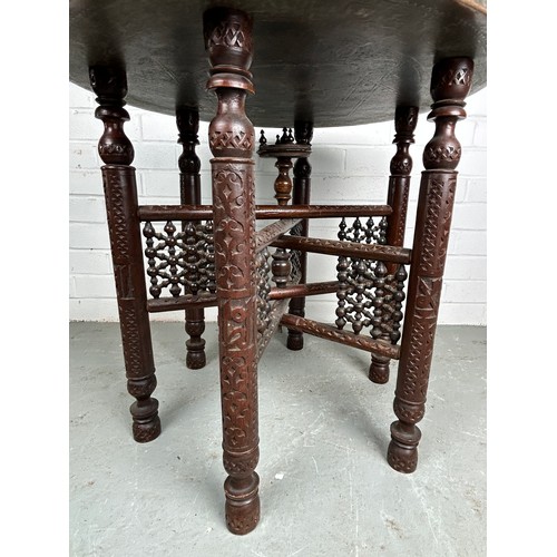 478 - A 19TH CENTURY MOROCCAN FOLDING TABLE, with a brass tray top, 64cm diameter x 57.5cm h 

Used condit... 