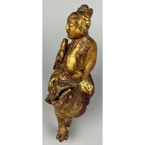 118 - A CHINESE RED LACQUERED AND GILT WOOD FIGURE RIDING A LION, 

21cm x 19cm