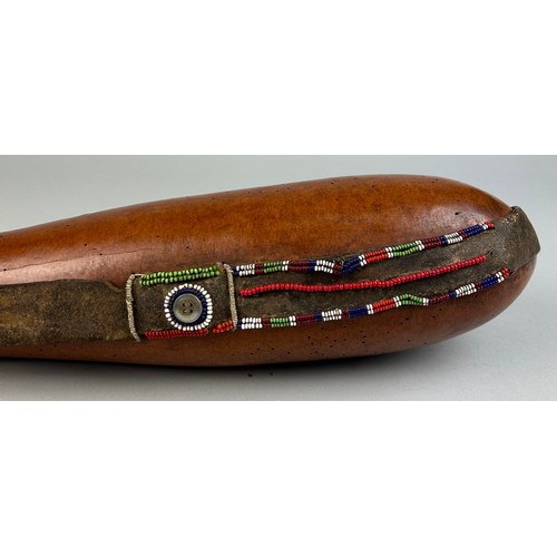 123A - A TRIBAL WATER FLASK WITH APPLIED BEADS

53cm in length.