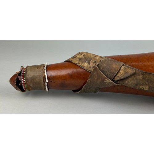 123A - A TRIBAL WATER FLASK WITH APPLIED BEADS

53cm in length.