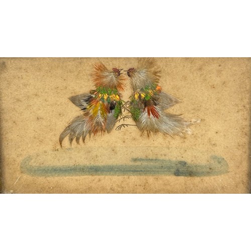 442 - COCKFIGHTING INTEREST: A FRAMED SET OF THREE WATERCOLOURS WITH APPLIED BIRD FEATHERS DEPICTING A COC... 