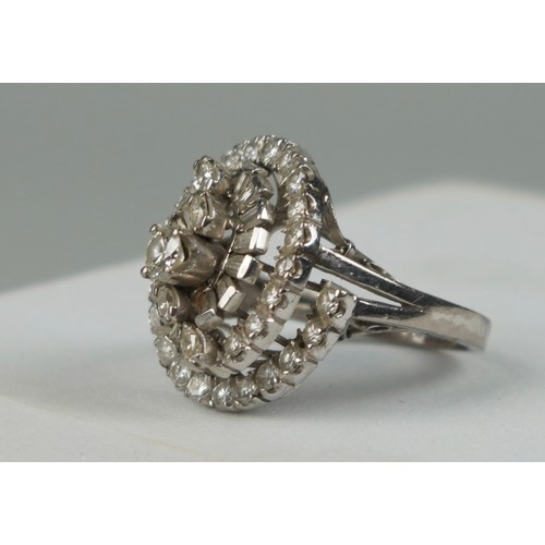 176 - AN 18CT WHITE GOLD RING OF 'WHIRL' DESIGN SET WITH DIAMONDS, 

Weight: 6.9gms 

One baguette cut dia... 