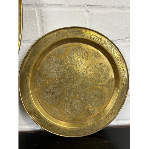 223 - A LARGE ISLAMIC BRASS DISH ALONG WITH A SMALLER EXAMPLE AND A COPPER DISH,

Largest 59cm D