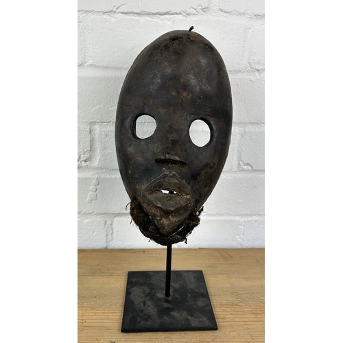 238 - AN AFRICAN TRIBAL MASK MOUNTED ON STAND,

24cm x 14cm 
On stand 32cm H