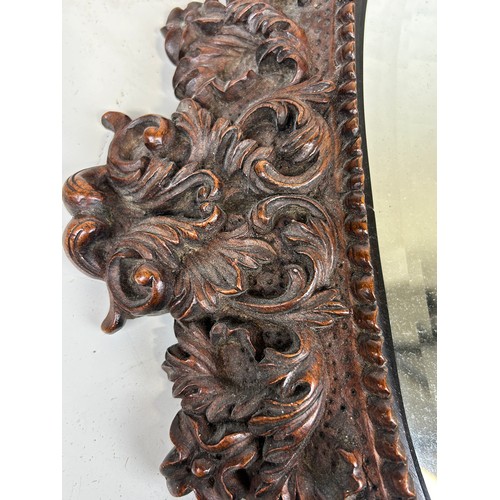 579 - A CONTINENTAL OAK WALL MIRROR PROFUSELY CARVED WITH FLORA AND FAUNA,

56cm x 43cm