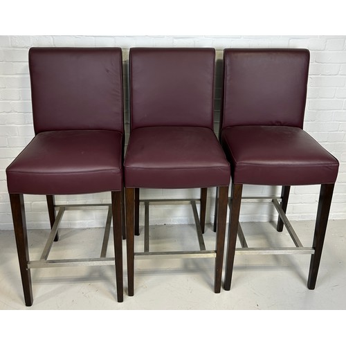 493 - A SET OF THREE BAR STOOLS BY BEN WHISTLER UPHOLSTERED IN BURGUNDY LEATHER WITH WHITE BUTTON BACK, 

... 