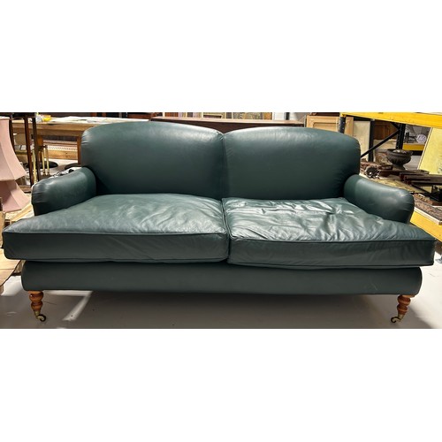 445 - A LARGE TWO SEATER HOWARD STYLE SOFA UPHOLSTERED IN GREEN LEATHER FABRIC, 

Raised on four legs, the... 