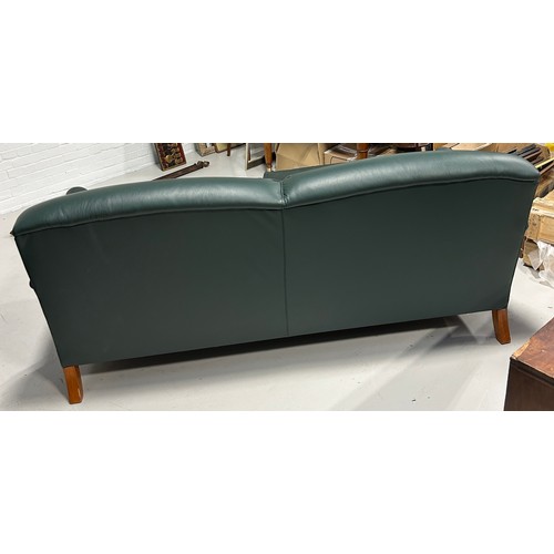 445 - A LARGE TWO SEATER HOWARD STYLE SOFA UPHOLSTERED IN GREEN LEATHER FABRIC, 

Raised on four legs, the... 