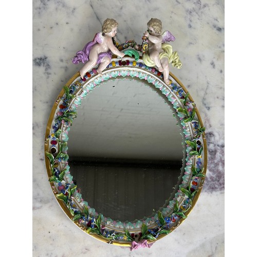 558 - A MEISSEN PORCELAIN MIRROR WITH WINGED PUTTI CREST AND FLORAL BORDER, 

34cm x 24cm