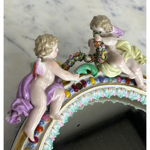 558 - A MEISSEN PORCELAIN MIRROR WITH WINGED PUTTI CREST AND FLORAL BORDER, 

34cm x 24cm