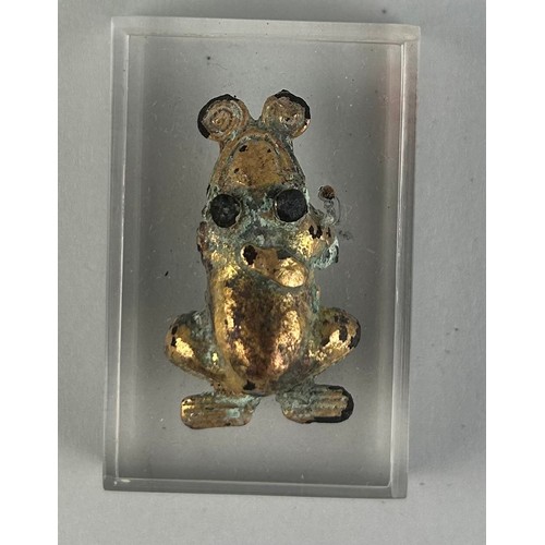 106 - A PRE-COLUMBIAN TUMBAGA FROG ORNAMENT, 

3.3cm x 2cm 

Mounted on perspex stand. 

4.5cm x 3cm