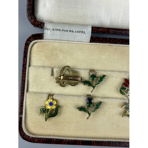 128 - A CASED SET OF FLORAL SILVER GILT AND ENAMEL LAPEL PINS MADE IN ENGLAND, 

Case marked 'Zarger'.