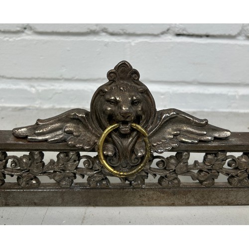 779 - AN ANTIQUE METAL FIRE FENDER DECORATED WITH WINGED LIONS HEAD MASKS AND PAW FEET, 

98cm x 31cm