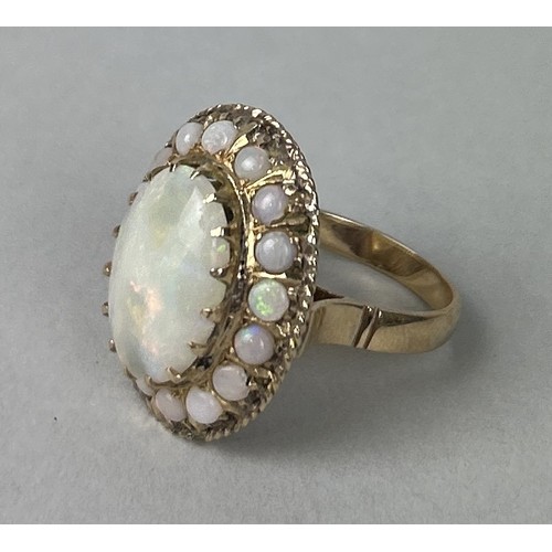 37 - A 14CT GOLD RING SET WITH A LARGE CENTRAL OPAL SURROUNDED BY SMALLER OPALS Weight: 7.3gms