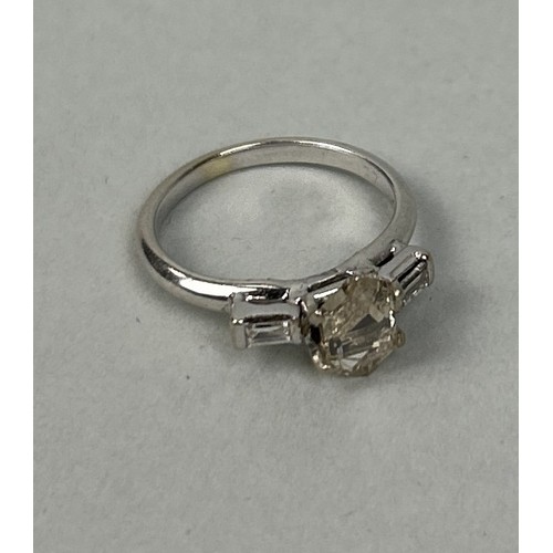 209 - A TRAPEZE CUT DIAMOND THREE STONE PLATINUM RING Center stone approximately 1ct Weight: 2.6 gms