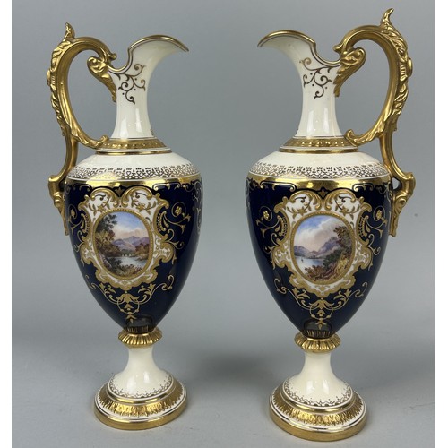 667 - A PAIR OF COALPORT PORCELAIN EWERS BLUE GROUND WITH GILT AND CENTRAL PAINTED PANELS DEPICTING LANDSC... 