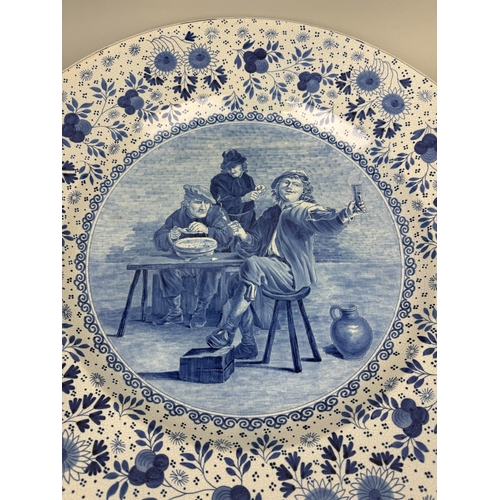 296 - A VERY LARGE DUTCH DELFT BLUE AND WHITE CHARGER CIRCA 1900
Painted with a Dutch Old master tavern sc... 