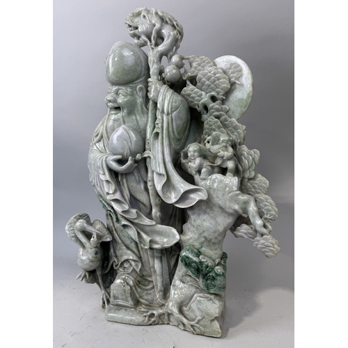 151 - A CHINESE JADE OR JADEITE SCULPTURE DEPICTING THE LUOHAN WITH A DRAGON STAFF, CHILDREN, CRANES AND F... 