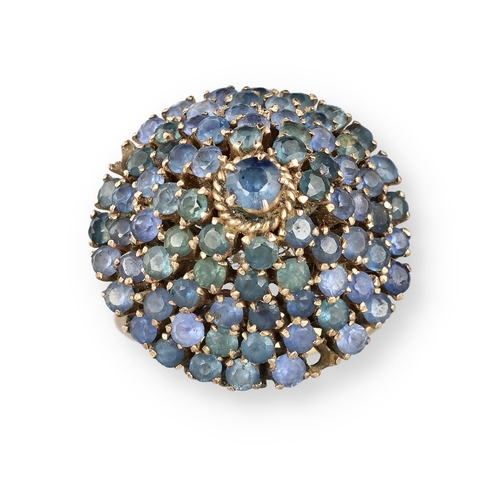 19 - AN 18 CARAT GOLD BOMBÉ RING, CLAW SET WITH FIVE ROWS OF SAPPHIRES
The central stone in a ropetwist s... 