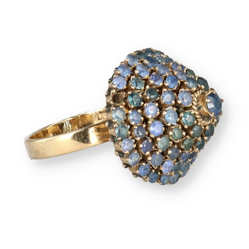 19 - AN 18 CARAT GOLD BOMBÉ RING, CLAW SET WITH FIVE ROWS OF SAPPHIRES
The central stone in a ropetwist s... 