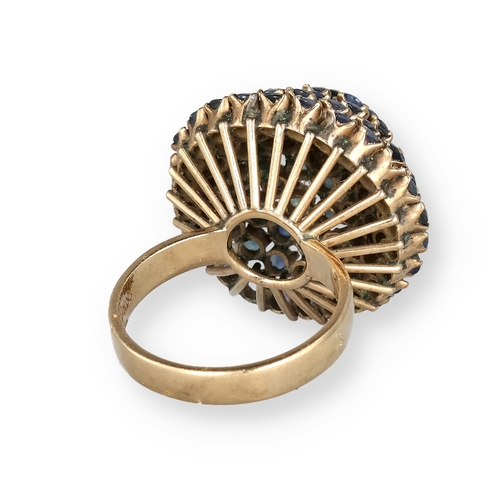 19 - AN 18 CARAT GOLD BOMBÉ RING, CLAW SET WITH FIVE ROWS OF SAPPHIRES
The central stone in a ropetwist s... 