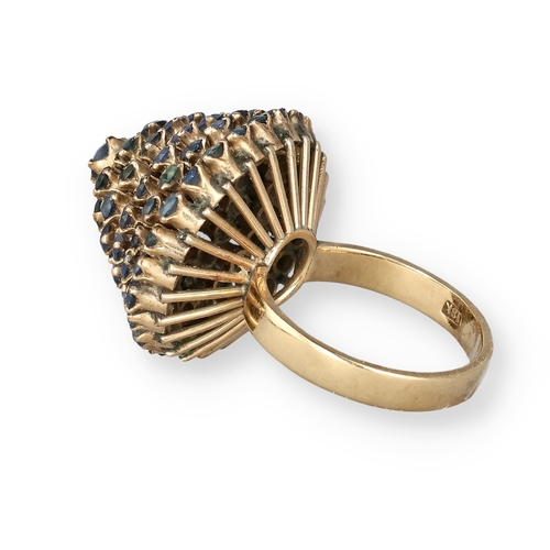 19 - AN 18 CARAT GOLD BOMBÉ RING, CLAW SET WITH FIVE ROWS OF SAPPHIRES
The central stone in a ropetwist s... 