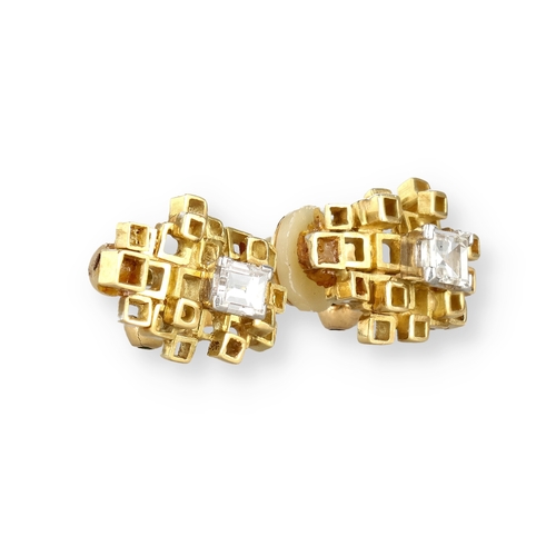 9 - A PAIR OF 18 CARAT GOLD EAR CLIPS, EACH CENTRED BY AN EMERALD CUT DIAMOND
Composed of irregular open... 