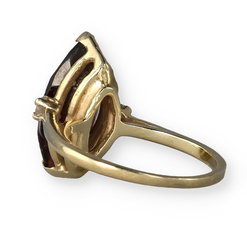 49 - A 14 CARAT GOLD GARNET AND DIAMOND THREE-STONE DRESS RING
The marquise cut garnet flanked by two bri... 
