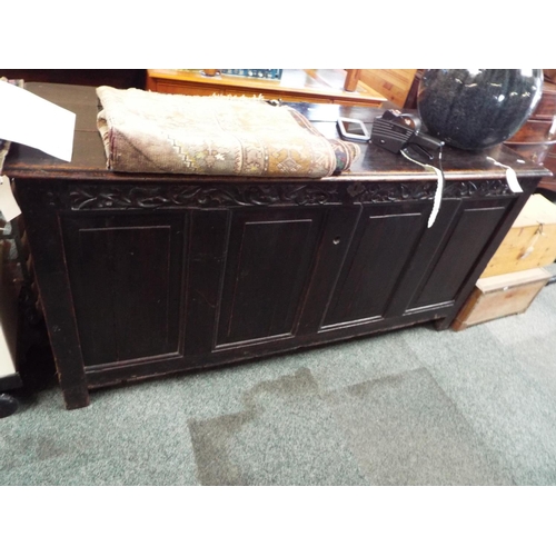 598 - A late 18thC early 19thC large oak coffer, the three plank top over a floral carved frieze and four ... 