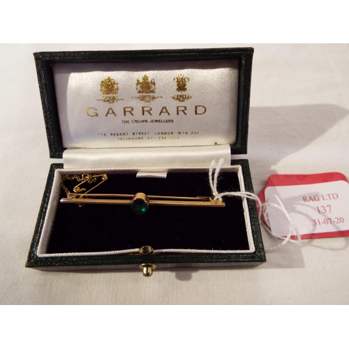 137 - A 9ct gold bar brooch inset with central emerald housed in a Garrard of London box