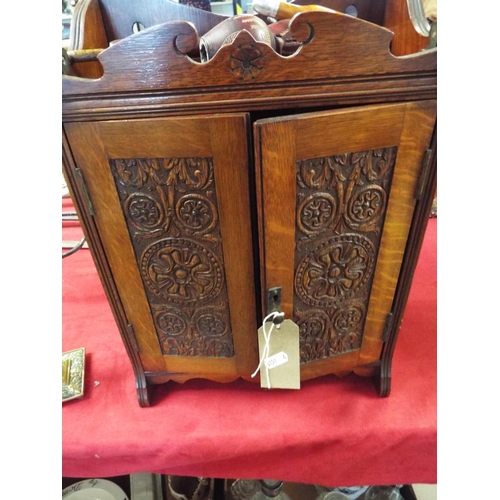 202 - A vintage smokers cabinet and contents having carved double doors enclosing inner compartment and pi... 