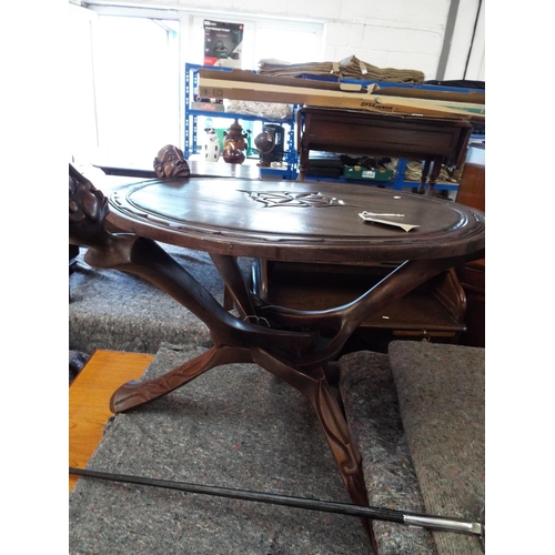 726 - A carved African table with a round top, supported with three folding legs carved with male heads