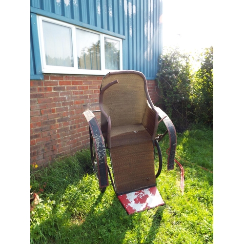 555 - A vintage rickshaw, the wicker panelled seating compartment for two with red painted arms