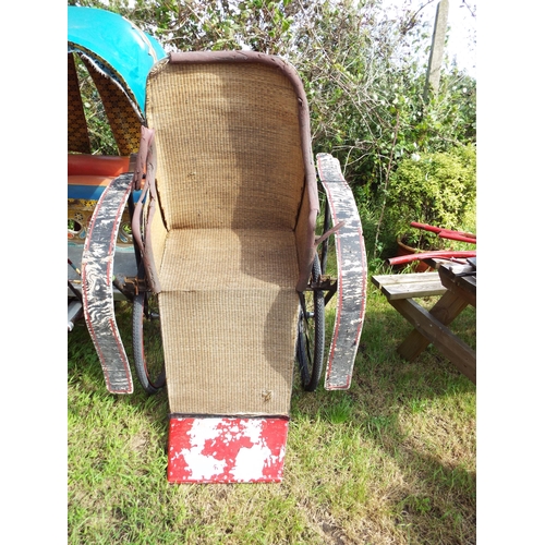 555 - A vintage rickshaw, the wicker panelled seating compartment for two with red painted arms