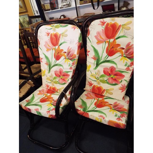 A pair of black painted bamboo conservatory rocking chairs with floral ...