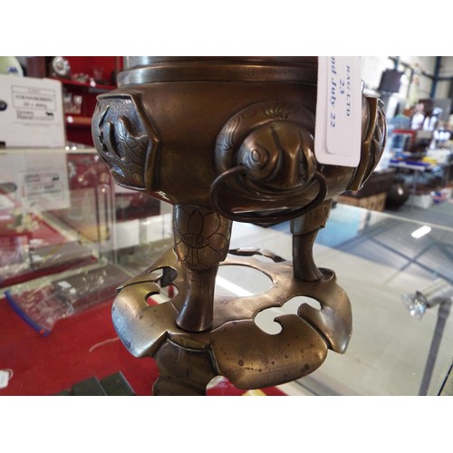 23 - A bronze Oriental tripod censer with a Fu dog mounted on cover and animals and bird decoration in re... 